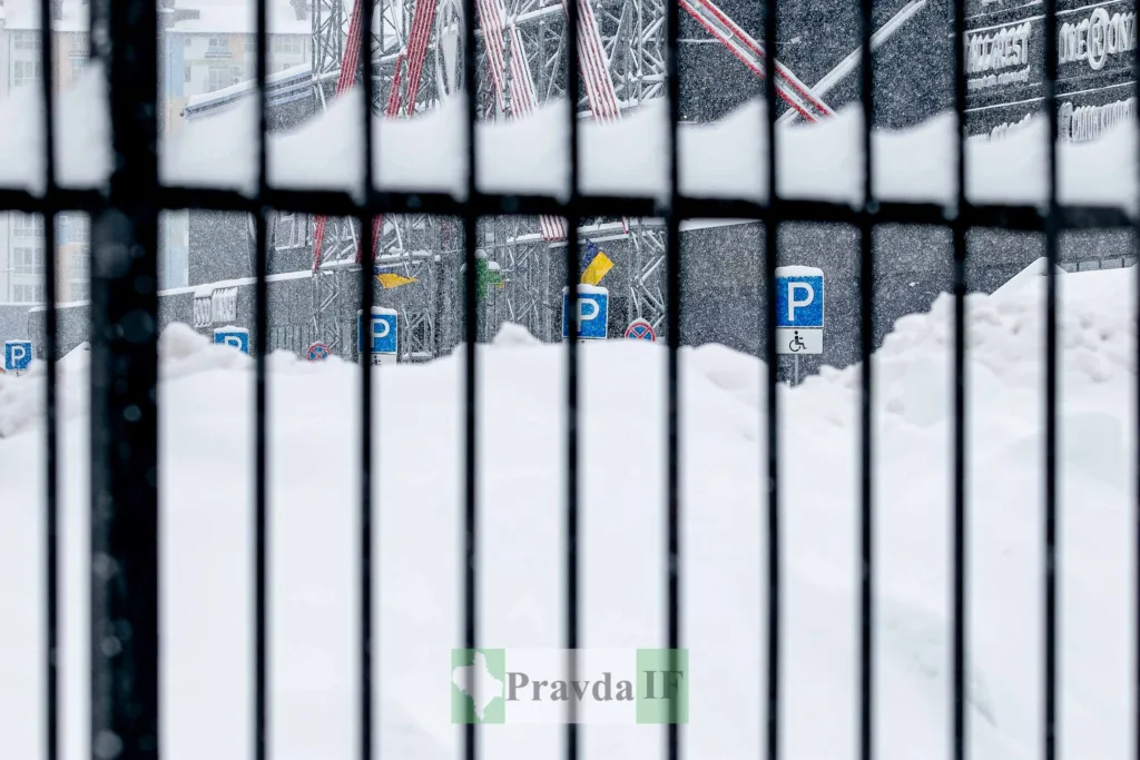 Засніжена парковка за металевою огорожею