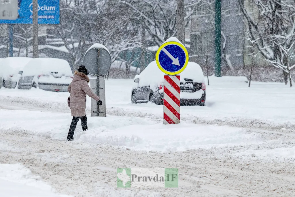 Людина переходить засніжену вулицю під час хуртовини
