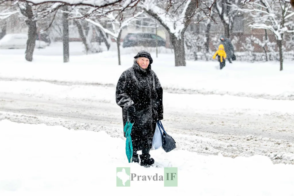 Жінка йде сніжною вулицею взимку