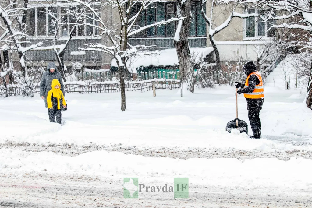 Прибиральник чистить сніг на засніженій вулиці