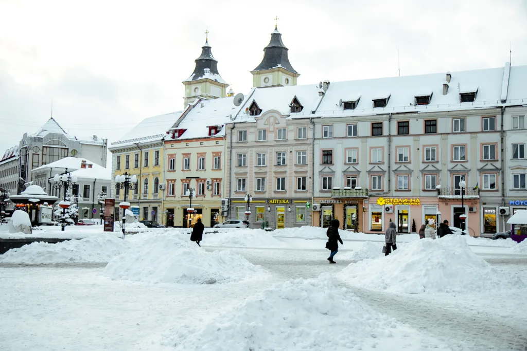 Засніжена площа з людьми та історичними будівлями
