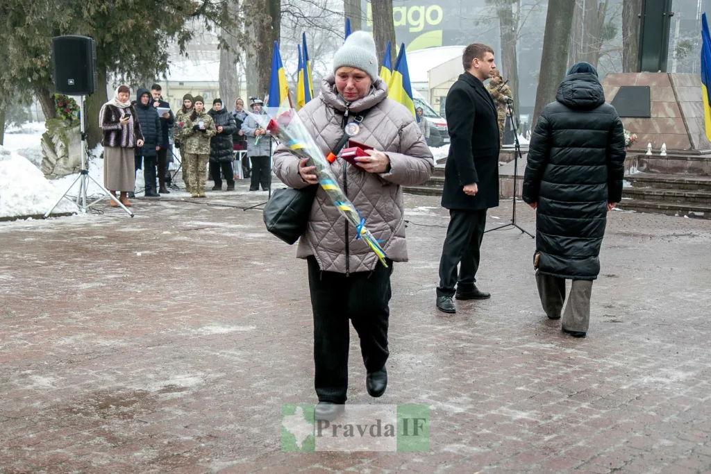 Жінка з квітами на меморіальній церемонії взимку