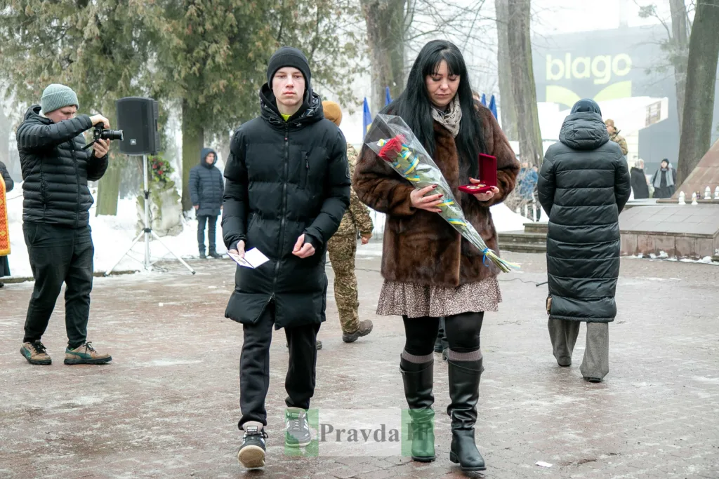 Люди несуть квіти на зимовому меморіалі