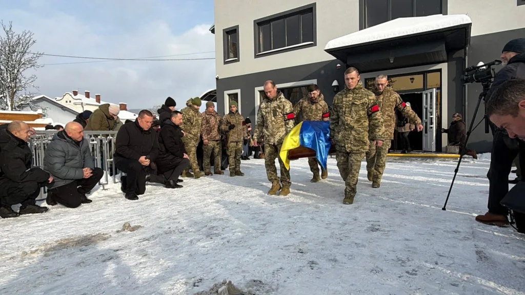 Військові несуть труну, накриту прапором України