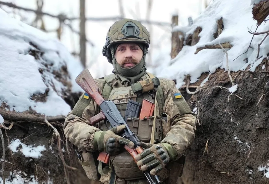 Український військовий у зимовому окопі з гвинтівкою