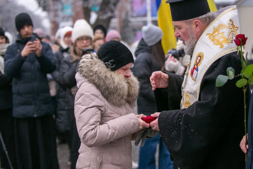 Священник вручає нагороду жінці на церемонії