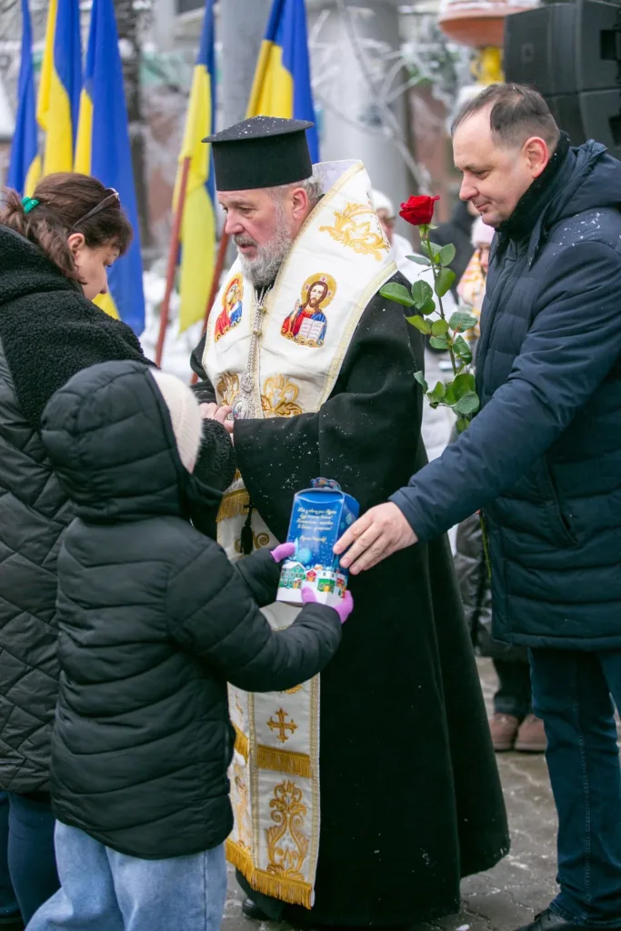 Священник благословляє дитину під час зимового свята