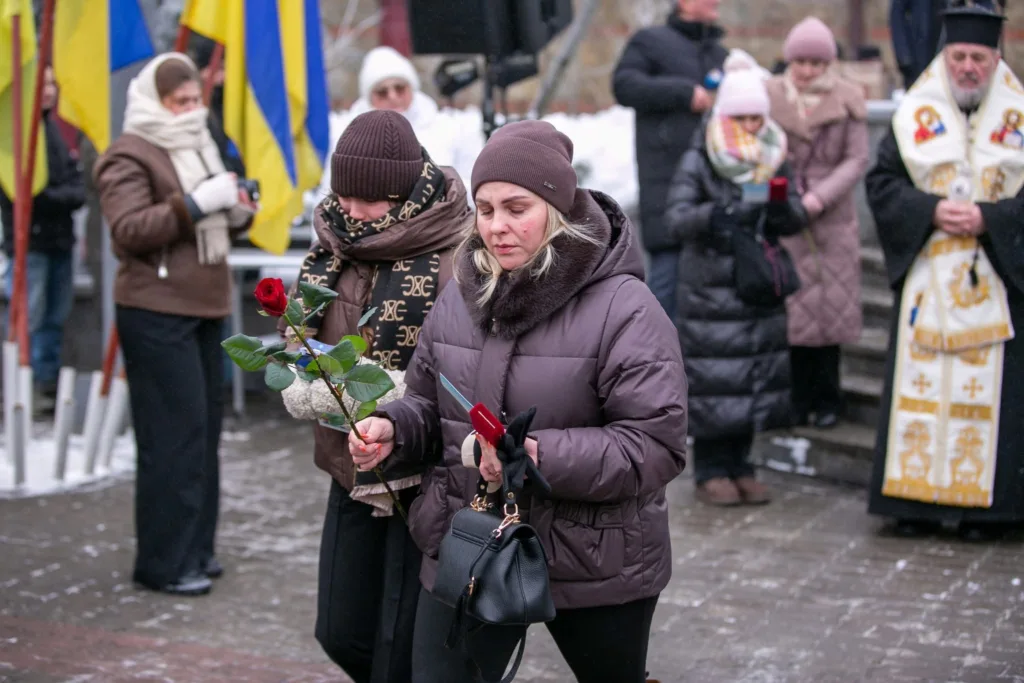 Люди з квітами на меморіальній церемонії взимку