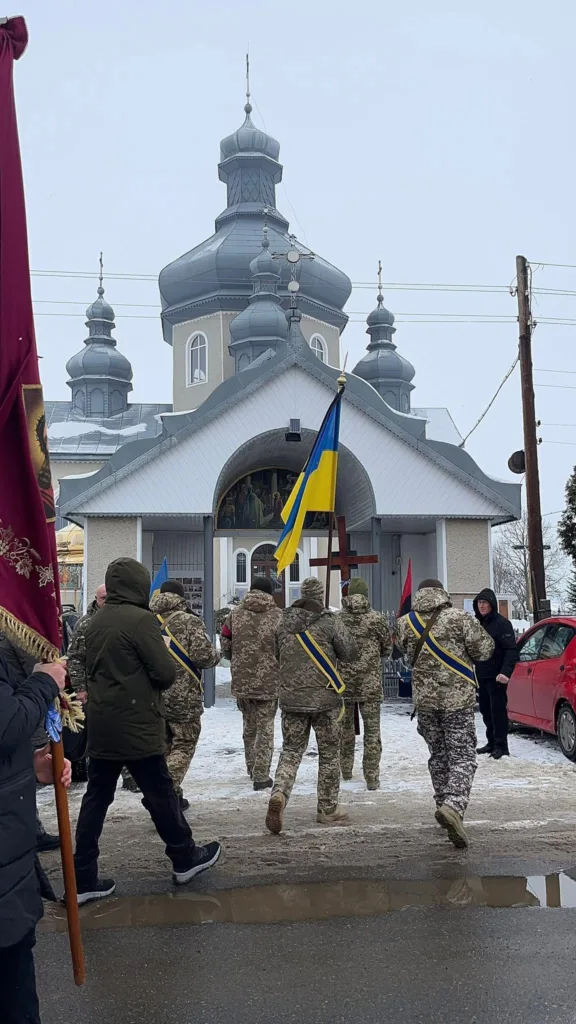 Військові з прапорами біля української церкви взимку
