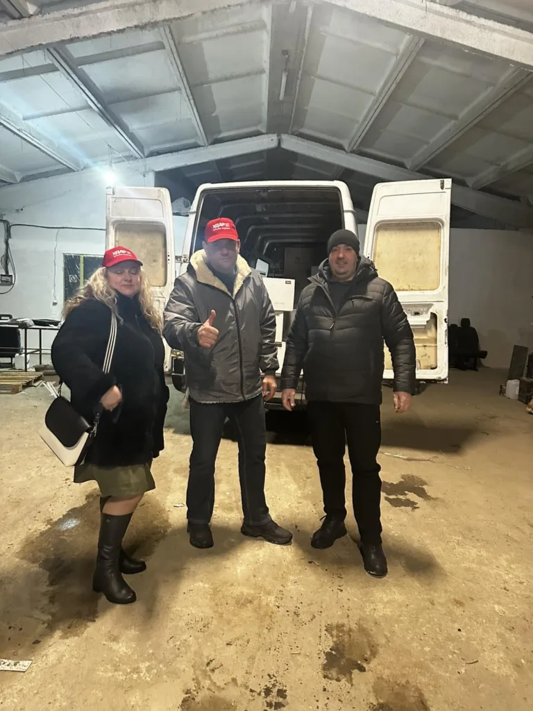 Троє людей стоять біля білого фургона в гаражі