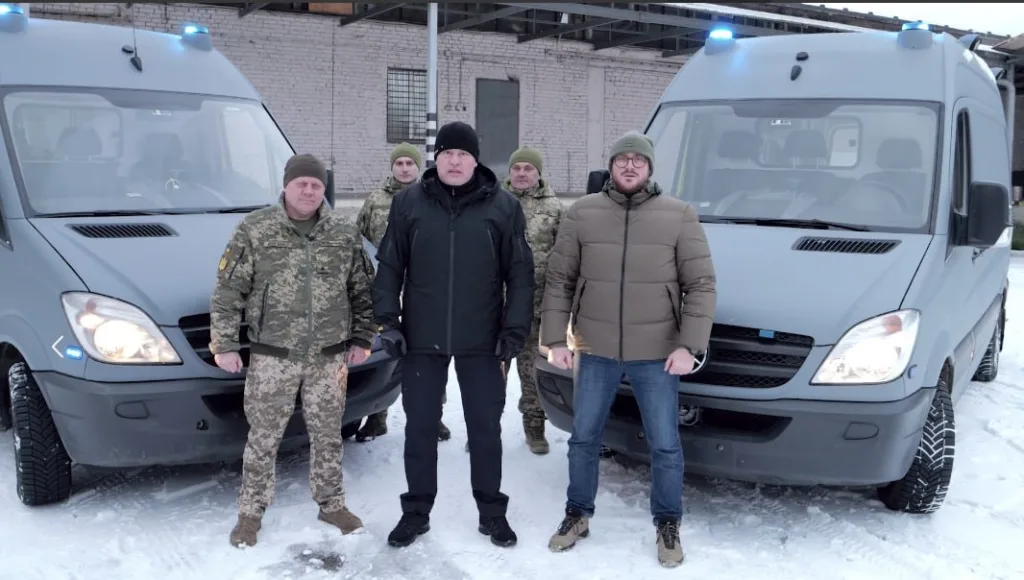 Військові біля двох сірих мікроавтобусів на снігу