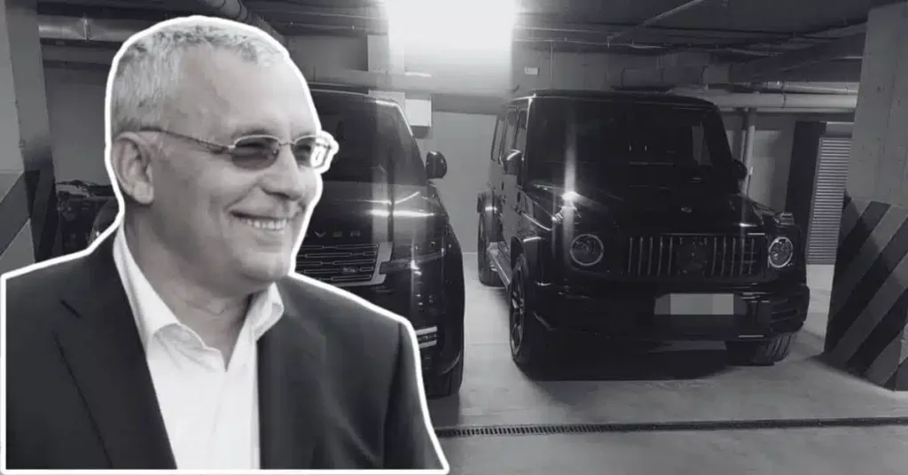 Чоловік у костюмі перед двома позашляховиками в гаражі