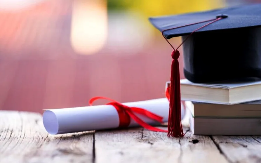 Диплом, книги та академічна шапка на столі