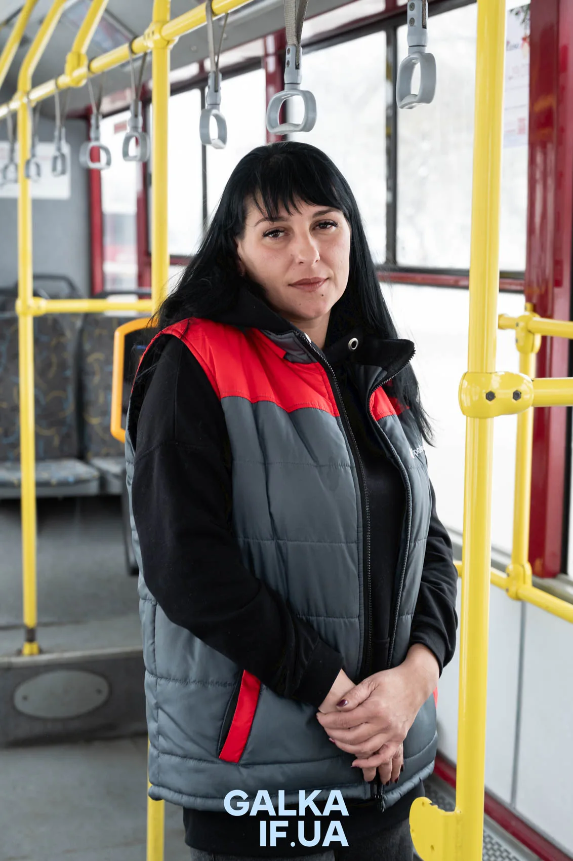 Жінка у маршрутці в червоно-сірій жилетці