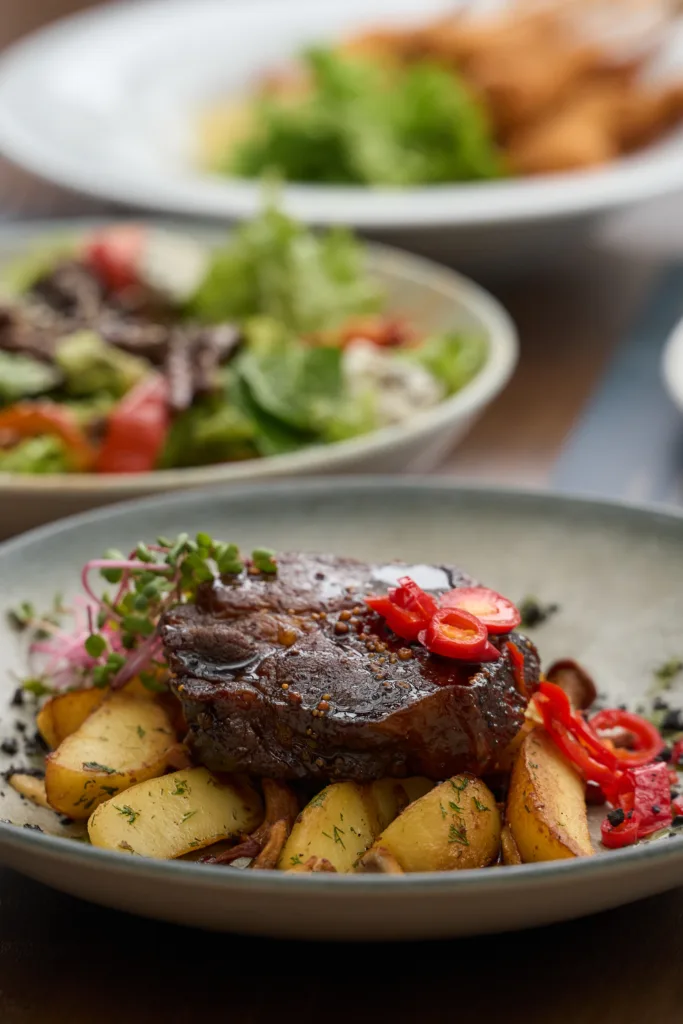 Стейк з картоплею та овочами на тарілці
