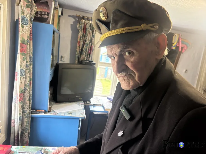 Літній чоловік у військовій формі стоїть у кімнаті