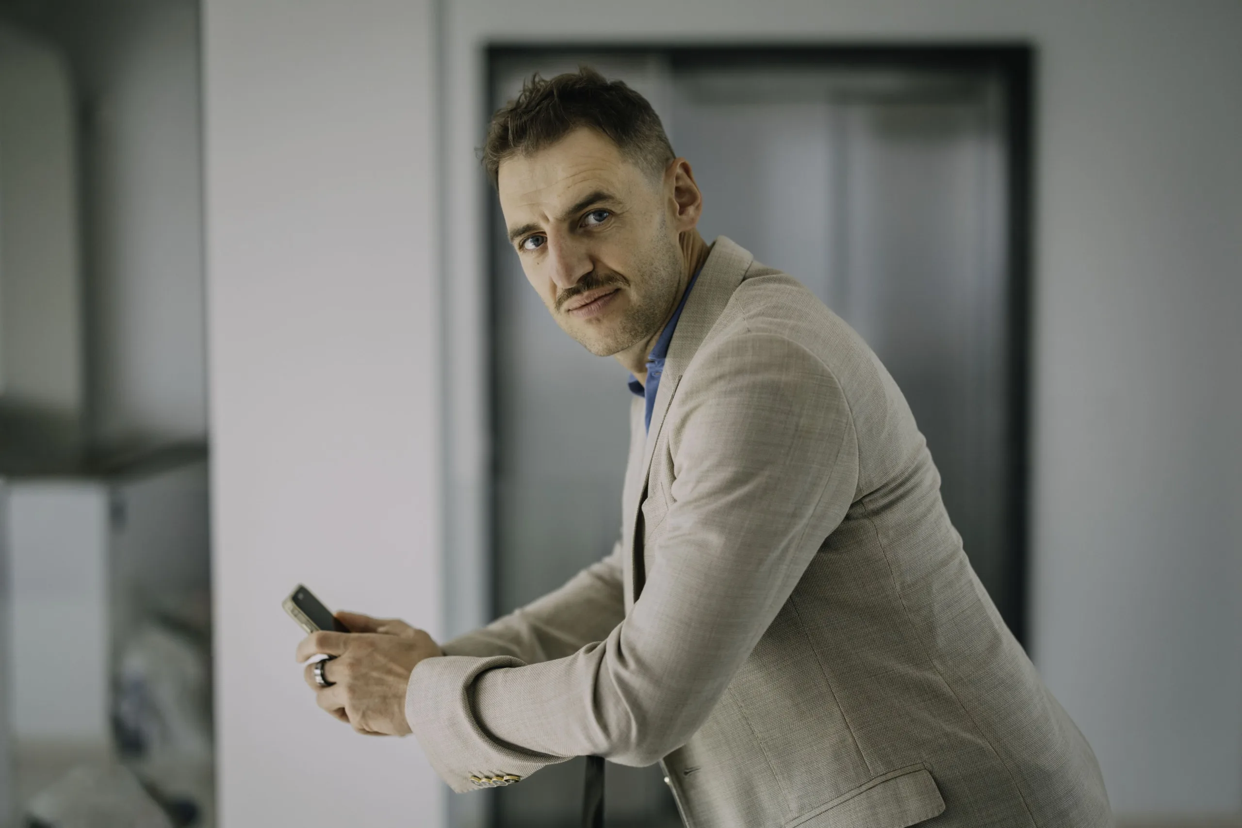 Чоловік у піджаку тримає смартфон в офісі