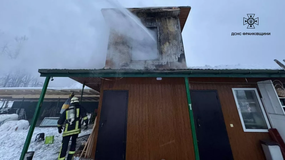 Пожежник гасить пожежу в двоповерховому будинку