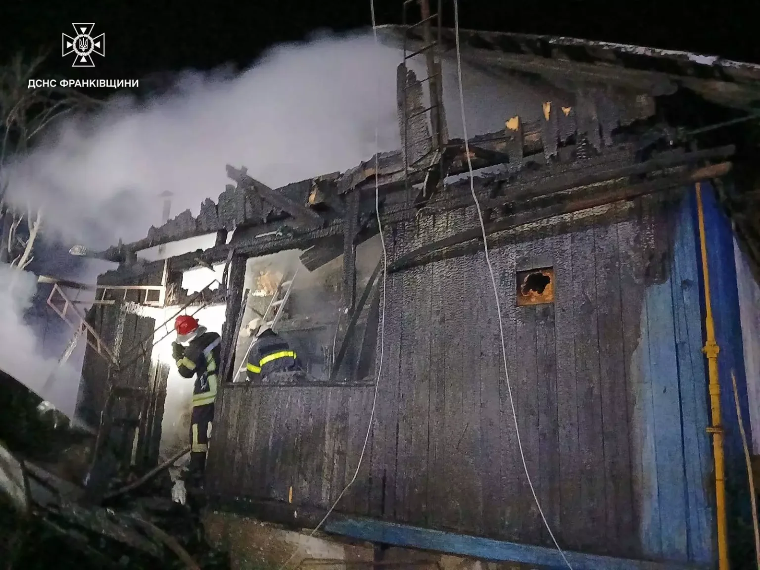 Пожежники гасять вогонь у дерев'яному будинку вночі