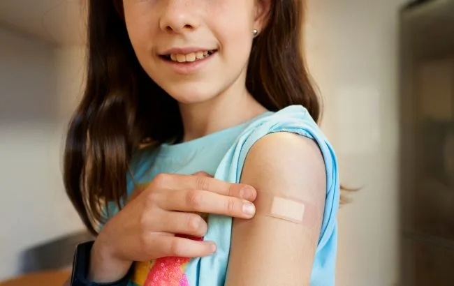 Дитина показує пластир після щеплення на руці