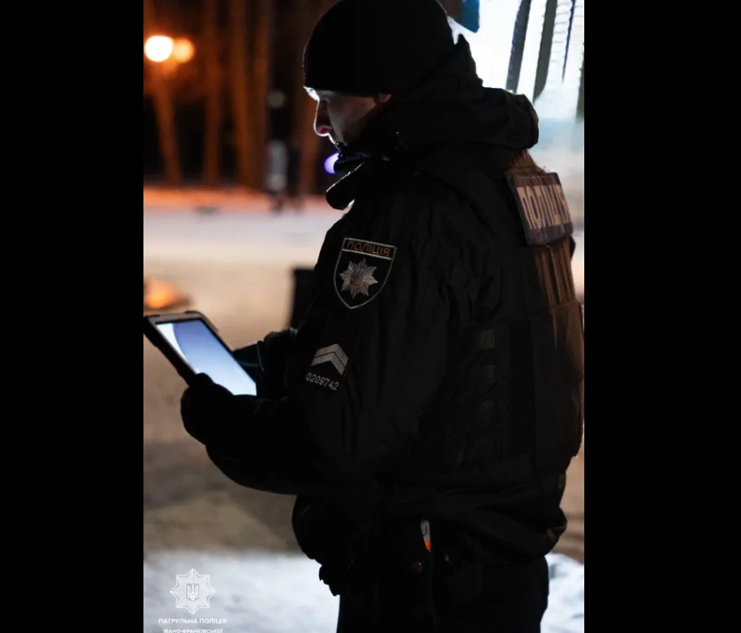 Поліцейський працює з планшетом на вулиці вночі