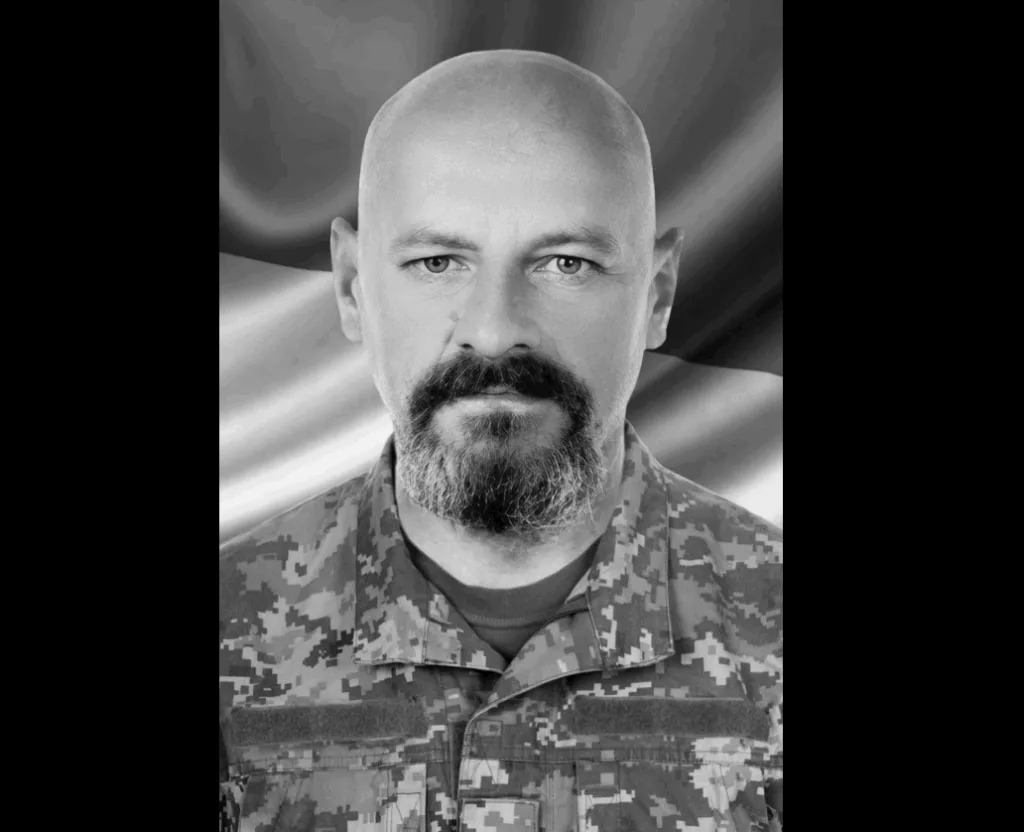 Український військовий у формі перед прапором України