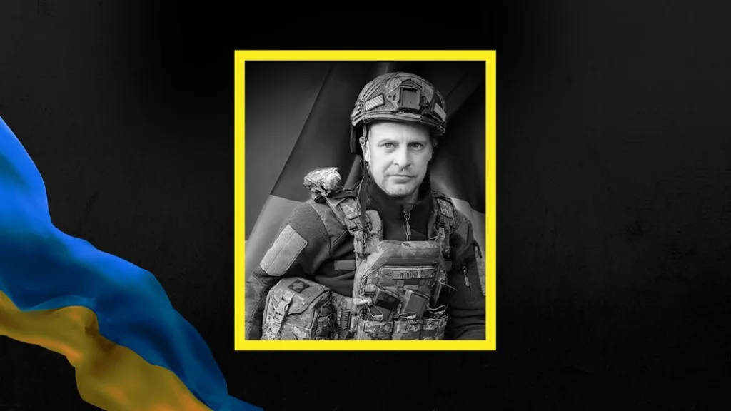 Український військовий у бронежилеті на тлі прапора