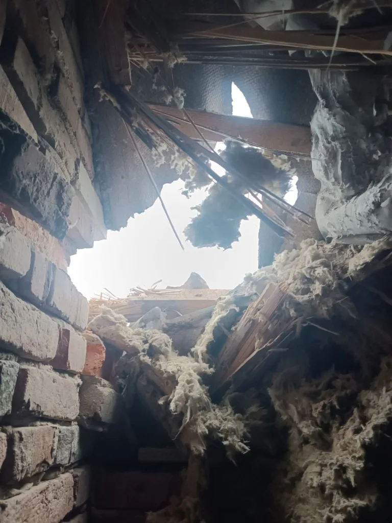 Зруйнована цегляна стіна та пошкоджений дах будівлі