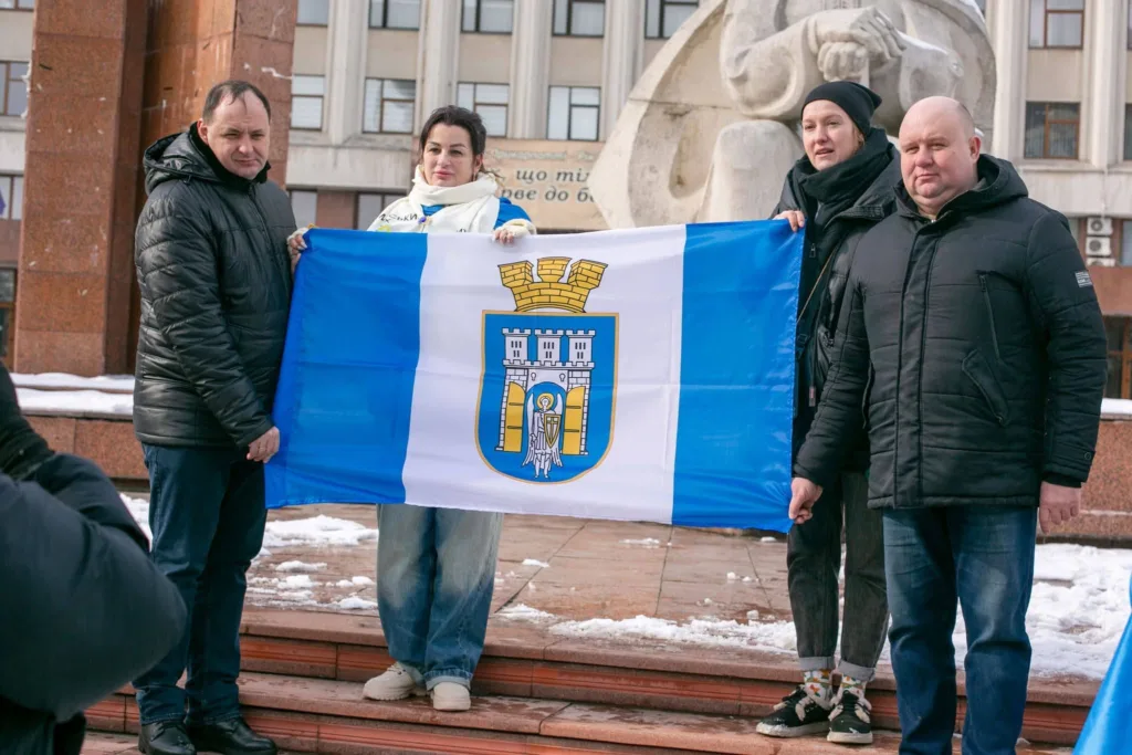Люди тримають прапор міста на вулиці