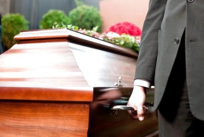 Чоловік несе дерев’яну труну на похороні