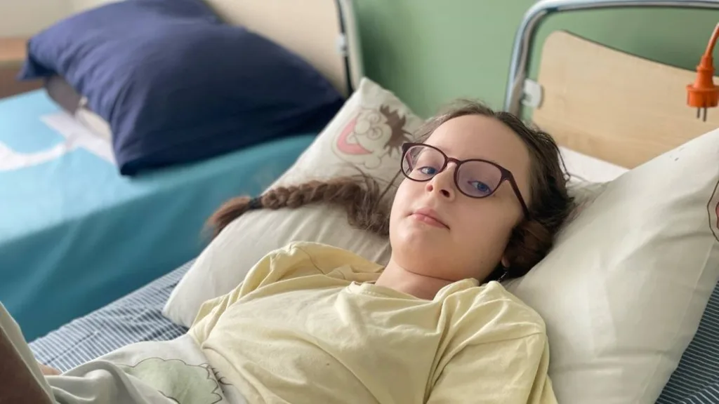 Дитина з окулярами лежить у лікарняному ліжку