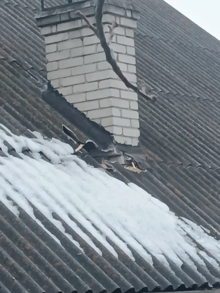 Пошкоджений дах біля цегляного димоходу взимку