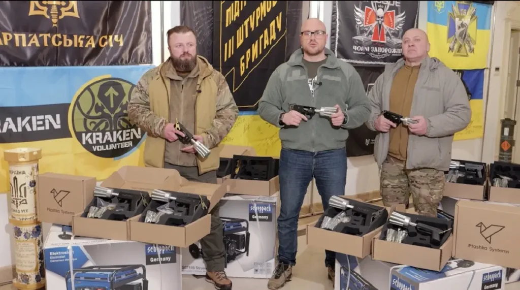 Волонтери демонструють обладнання перед прапорами України