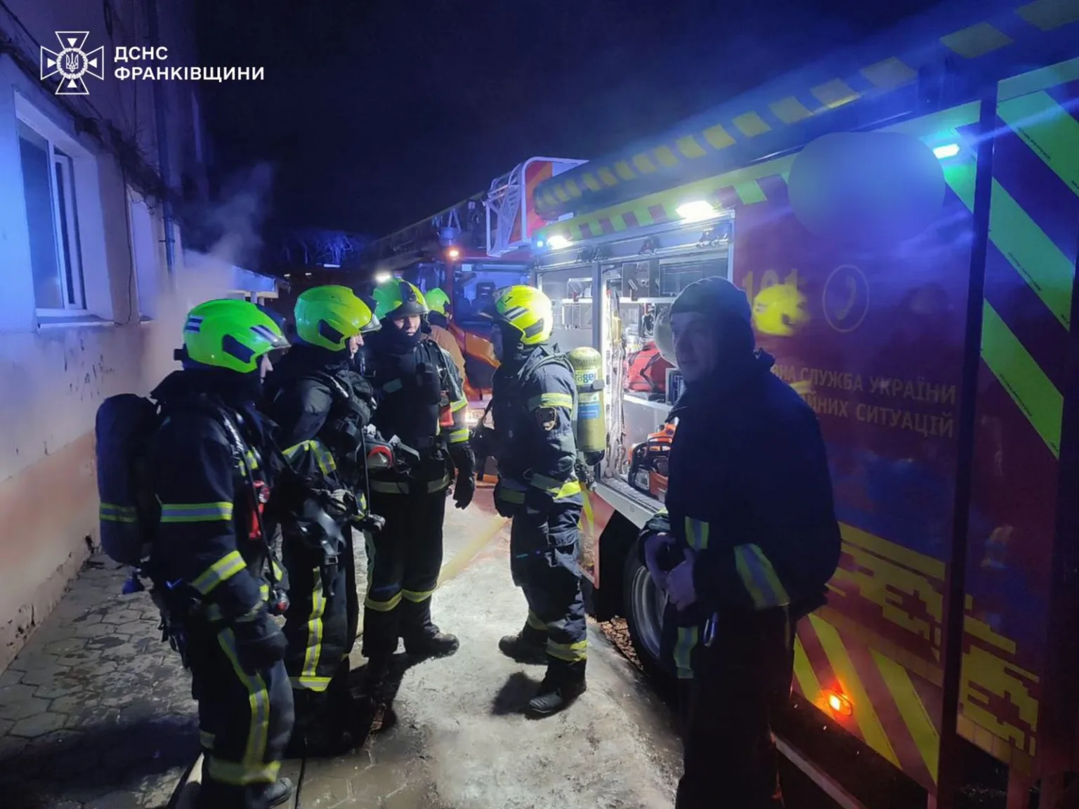 Пожежники біля пожежної машини вночі