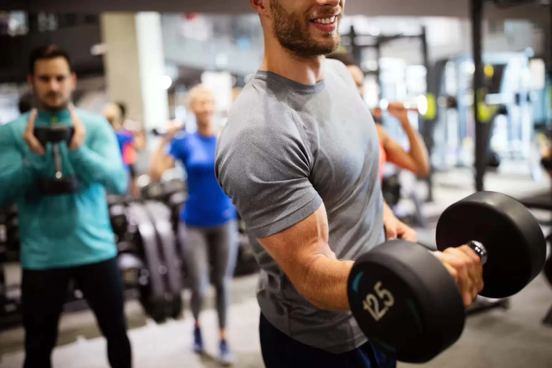 Чоловік тренується з гантелями у спортзалі