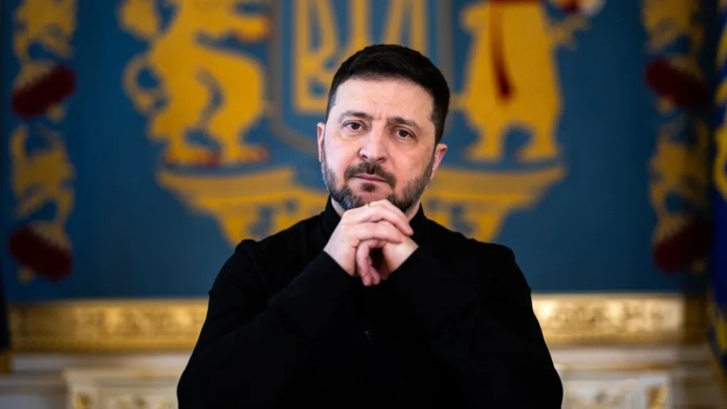 Чоловік стоїть перед синьо-золотим гербом України