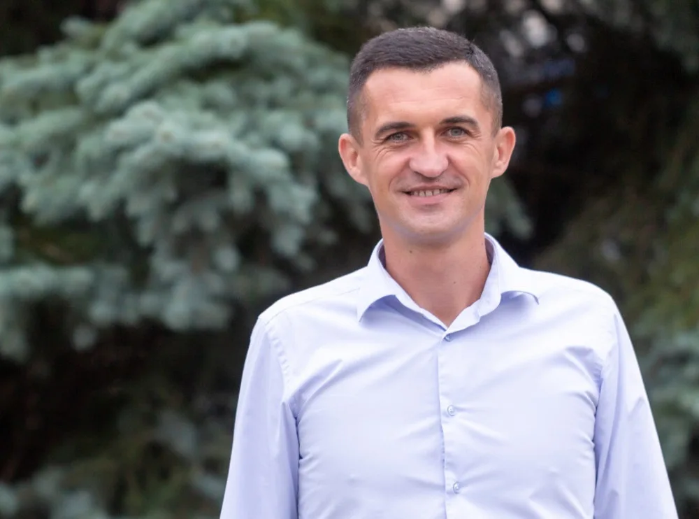 Усміхнений чоловік у білій сорочці на вулиці