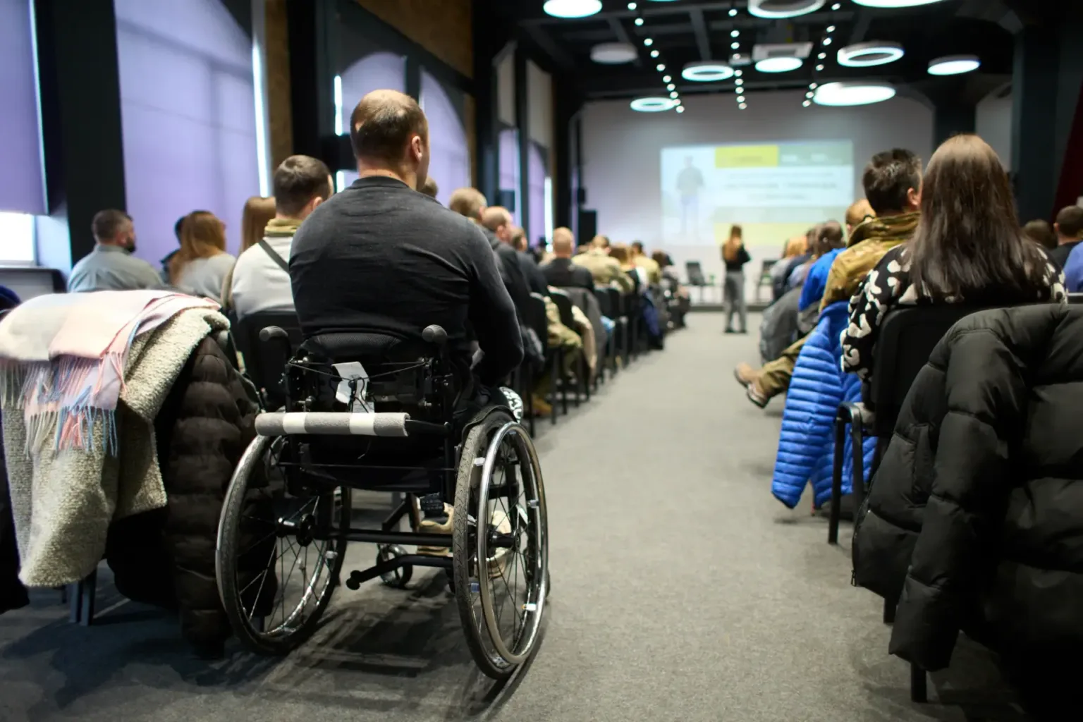 Люди на конференції, включаючи учасника у візку