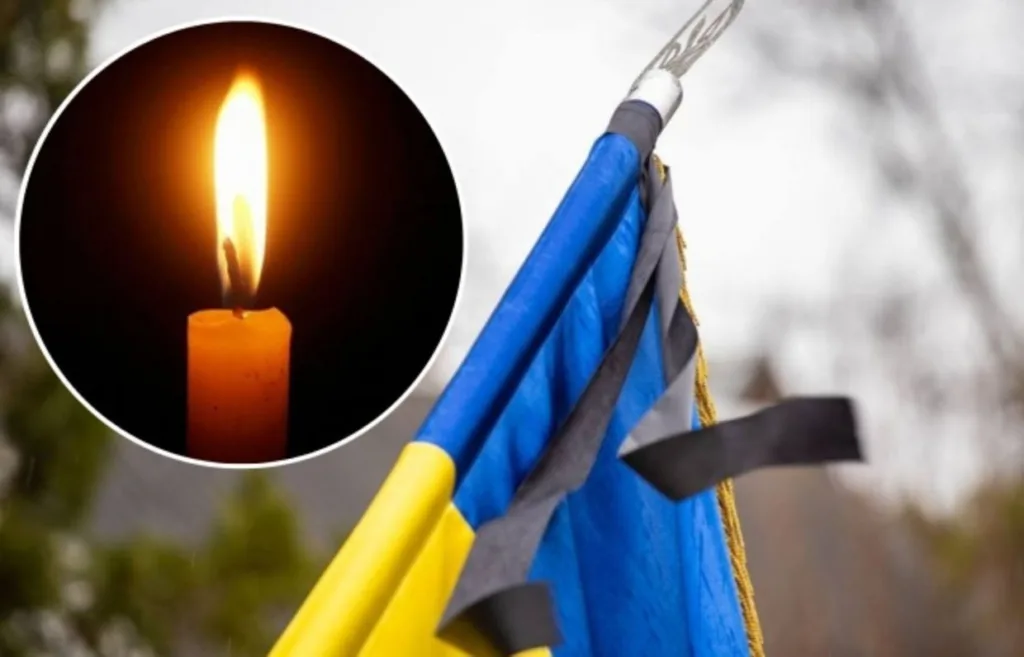 Запалена свічка та прапор України з траурною стрічкою