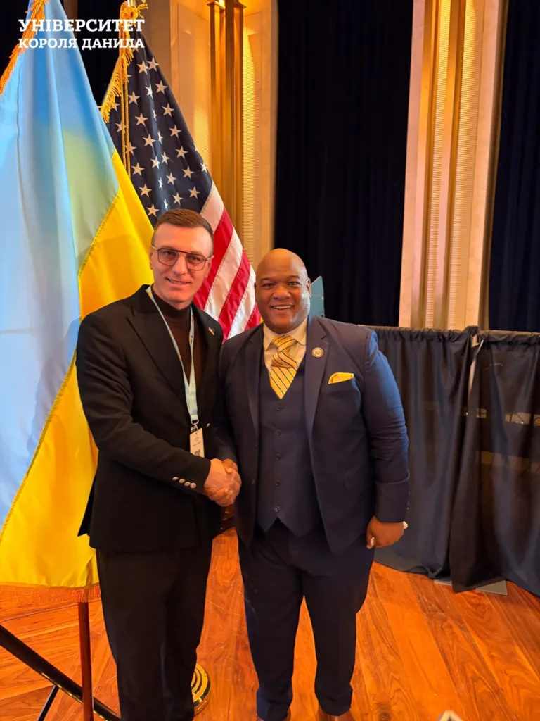 Двоє чоловіків потискають руки перед прапорами України і США