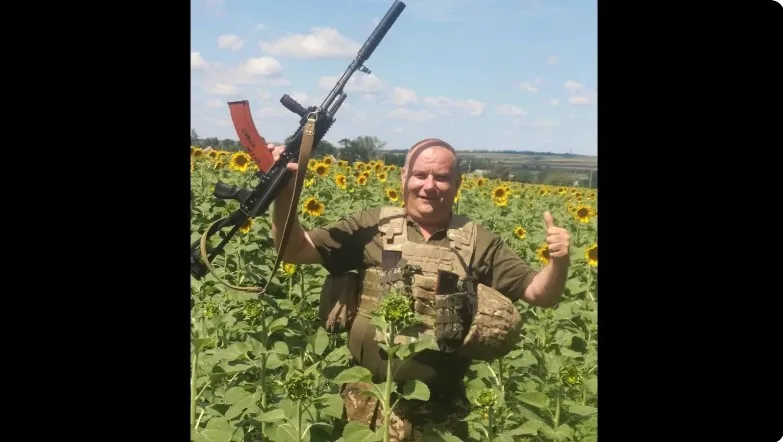 Військовий у полі соняхів з піднятою зброєю