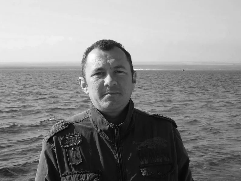 Чоловік стоїть біля моря у куртці