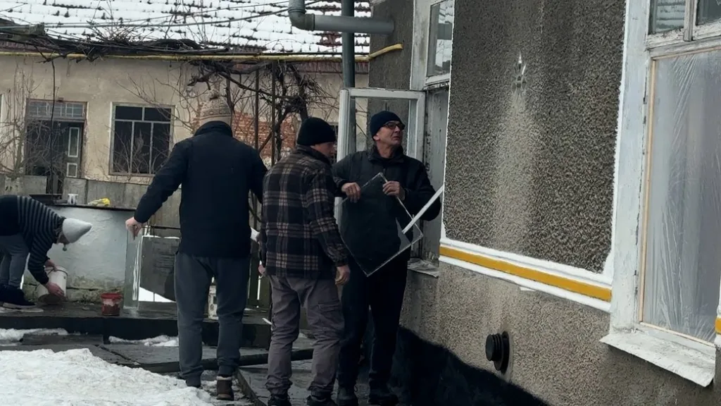 Чоловіки ремонтують вікна будинку взимку