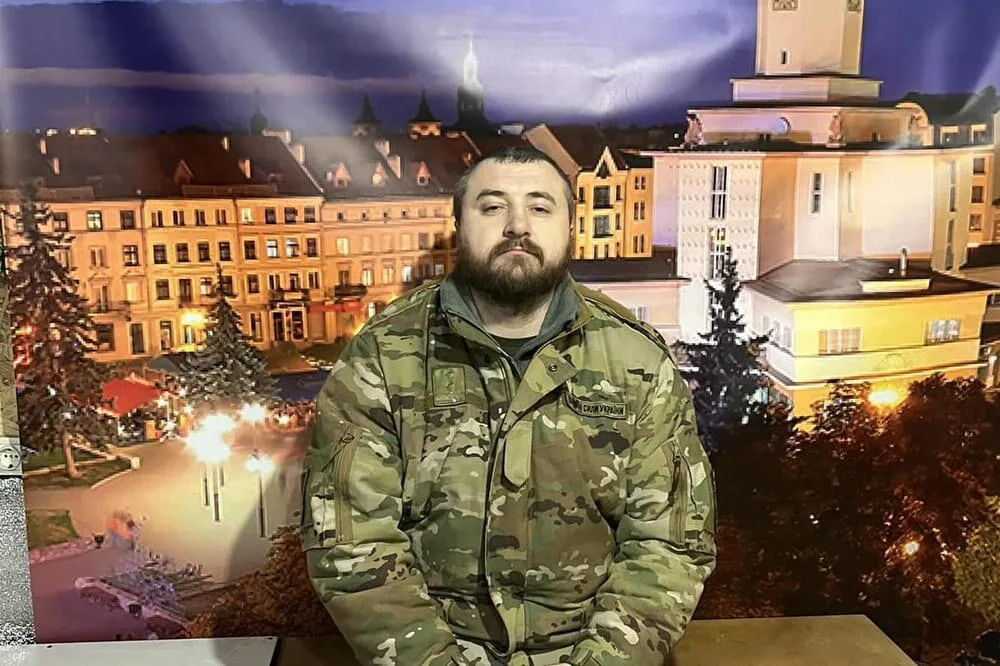 Військовий у камуфляжі на тлі міського пейзажу