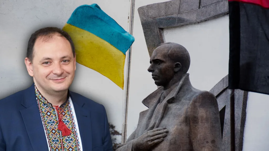 Чоловік у вишиванці біля пам’ятника та прапорів України