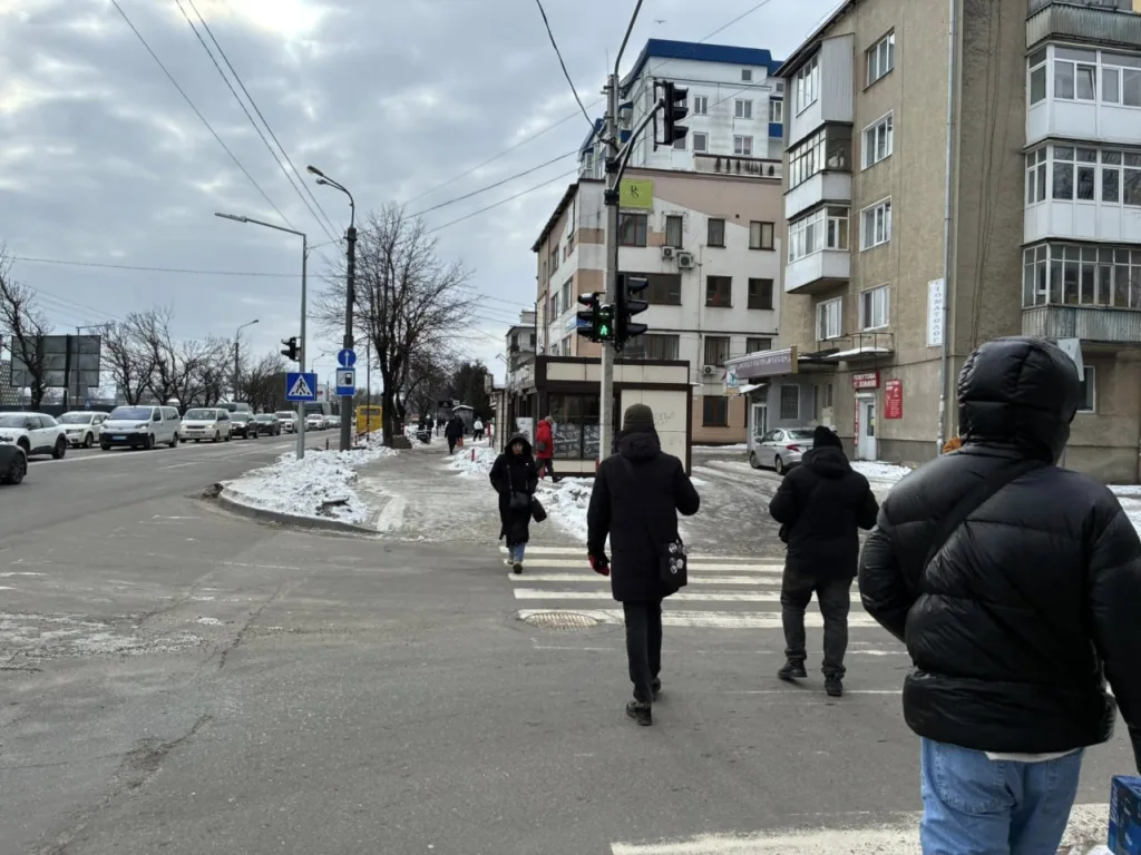 Пішоходи переходять зимову вулицю біля будинків