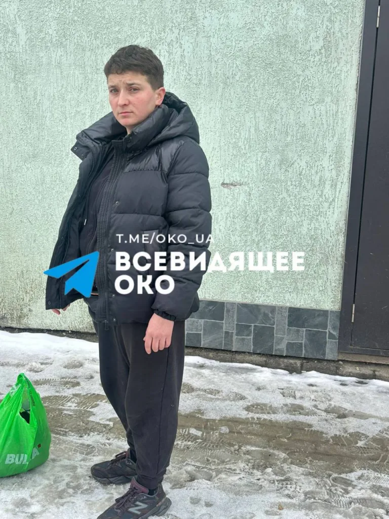 Людина стоїть на снігу біля стіни будівлі