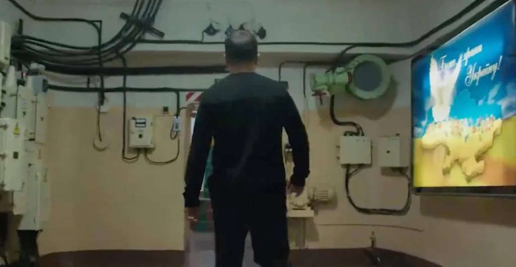 Чоловік у технічному приміщенні з плакатом України