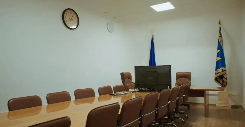 Порожня конференц-зала з великим столом і прапорами