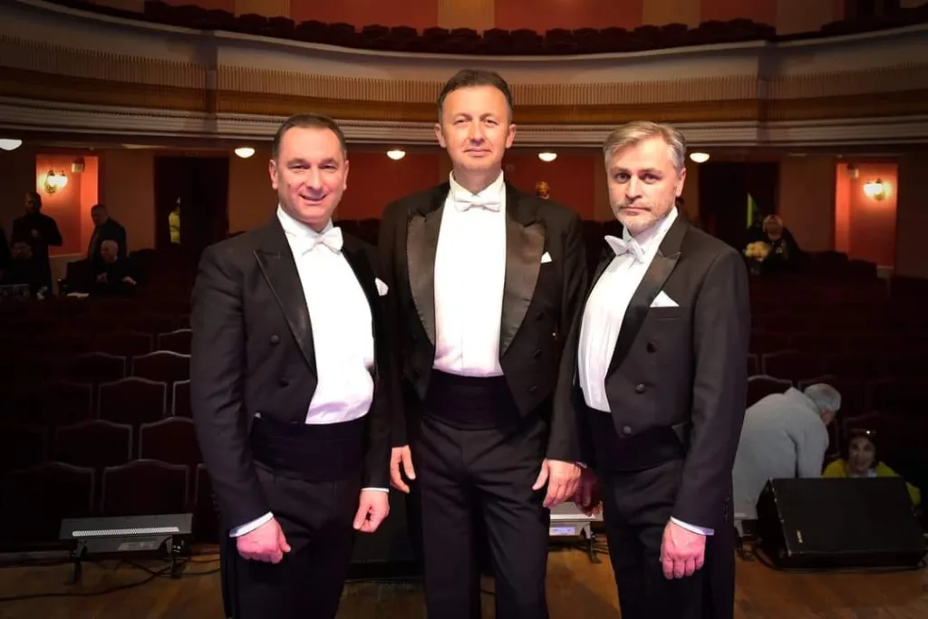 Три чоловіки у фраках на сцені театру